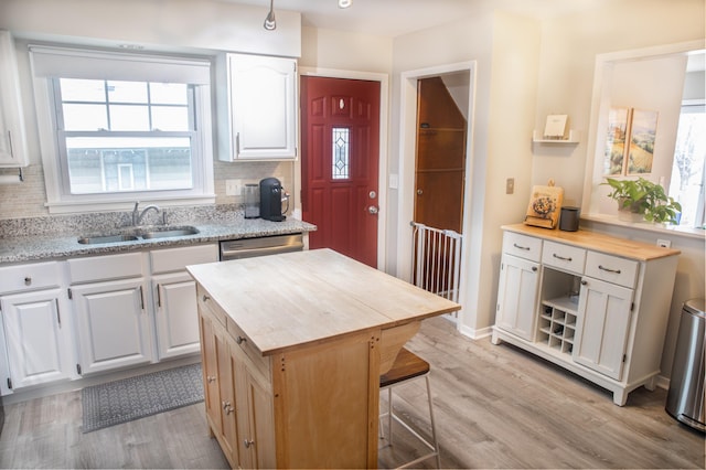 kitchen featuring sink, white cabinetry, backsplash, a kitchen island, and wood counters