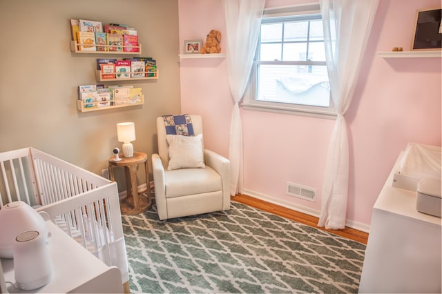 bedroom with wood-type flooring and a crib