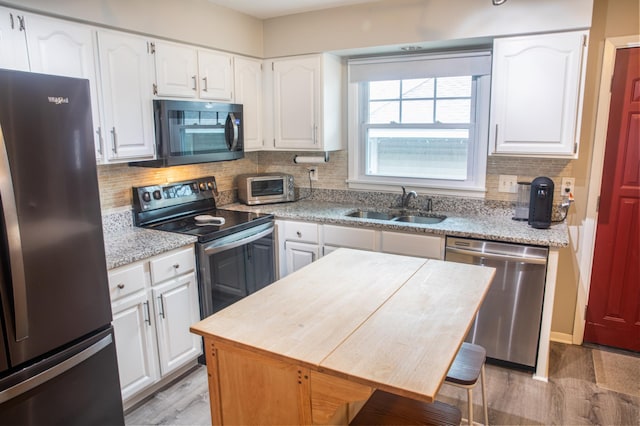 kitchen with appliances with stainless steel finishes, sink, white cabinets, backsplash, and a center island