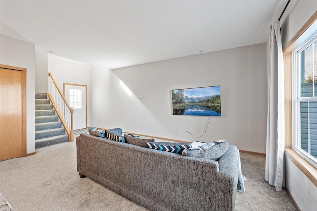 living area featuring baseboards, stairway, and light colored carpet