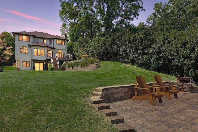 yard at dusk featuring a wooden deck and a patio area