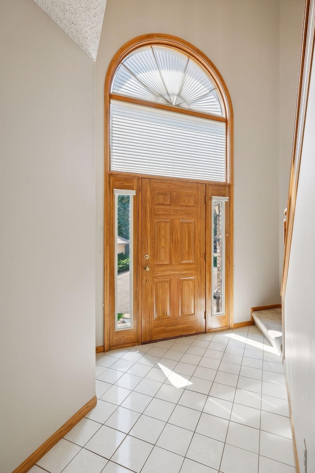 foyer entrance featuring light tile patterned floors and high vaulted ceiling