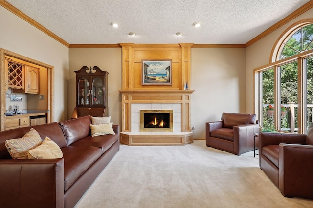 living room with bar, light carpet, a textured ceiling, ornamental molding, and a tiled fireplace