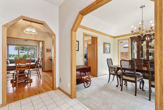 tiled dining area with a raised ceiling, a notable chandelier, and a textured ceiling