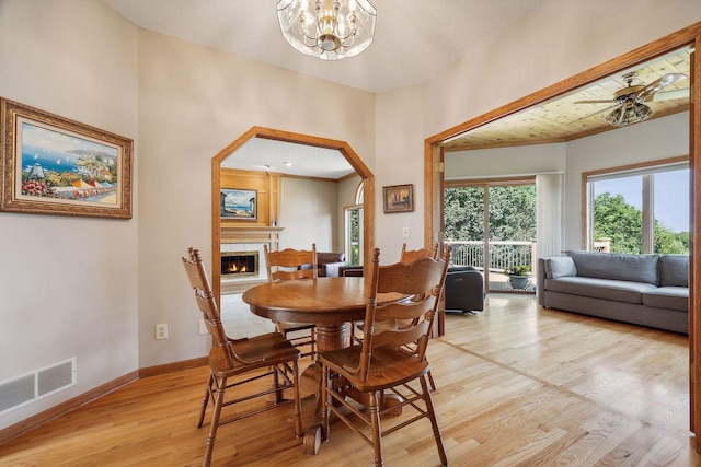 dining room featuring ceiling fan with notable chandelier and light hardwood / wood-style flooring