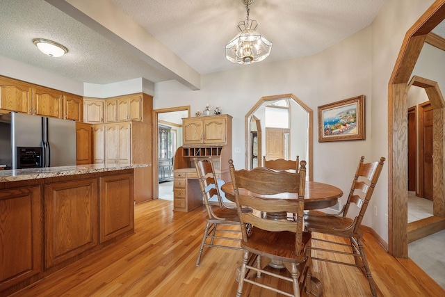 dining room with a chandelier, a textured ceiling, and light wood-type flooring