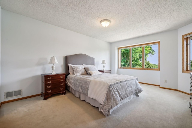 bedroom featuring light carpet and a textured ceiling