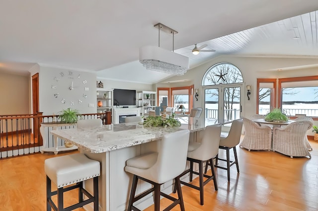 kitchen with light stone countertops, a center island, a breakfast bar area, and light hardwood / wood-style flooring