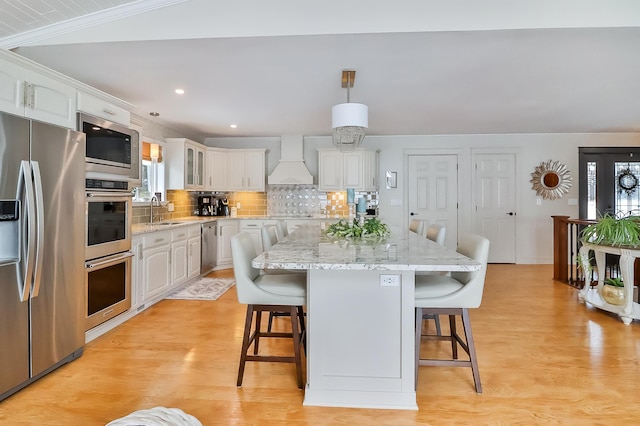 kitchen with stainless steel appliances, custom exhaust hood, a center island, and white cabinets