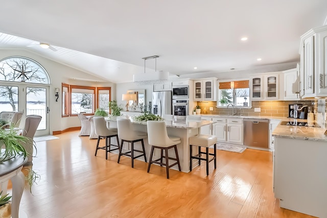 kitchen featuring hanging light fixtures, backsplash, stainless steel appliances, white cabinets, and a kitchen island