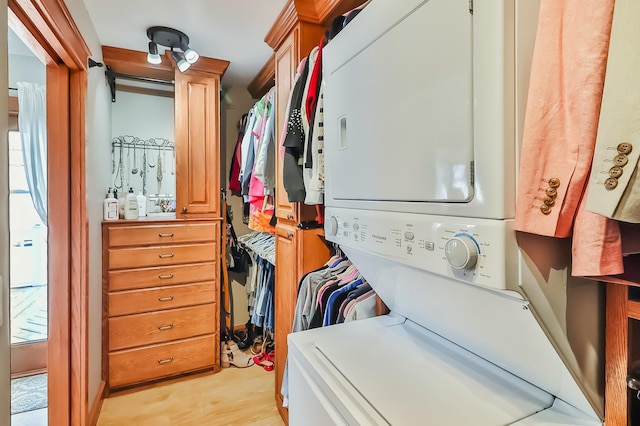 clothes washing area featuring stacked washing maching and dryer and light hardwood / wood-style floors