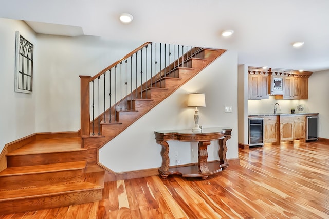 stairs with wine cooler, hardwood / wood-style flooring, and indoor wet bar