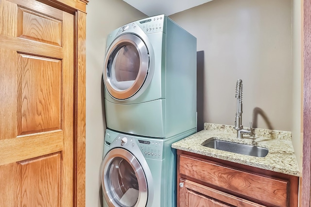 laundry room with cabinets, stacked washer and clothes dryer, and sink