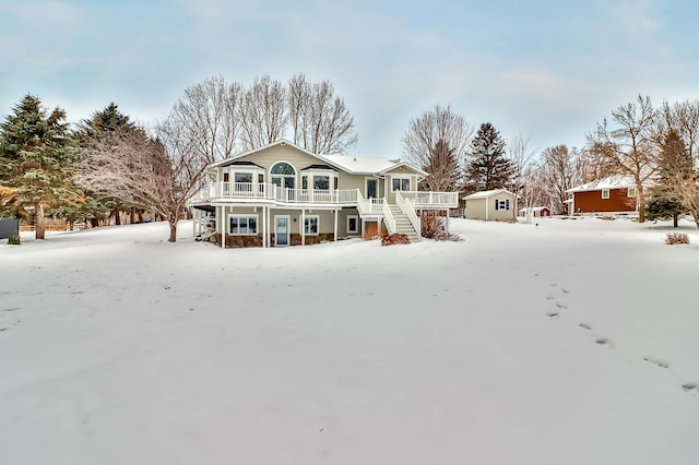 snow covered back of property with covered porch and a shed