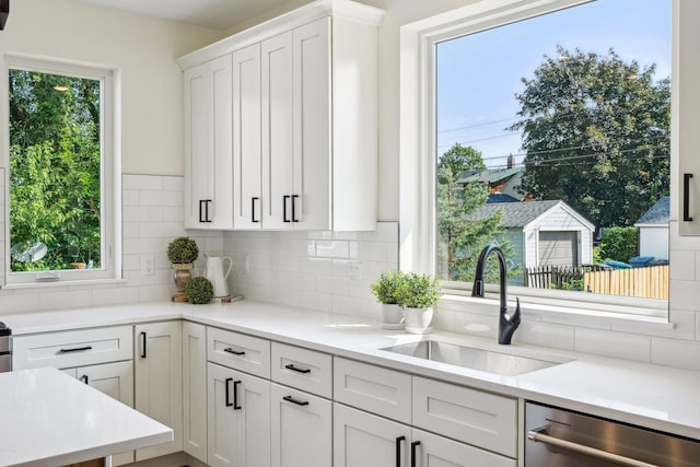 kitchen with white cabinets, backsplash, sink, and dishwasher