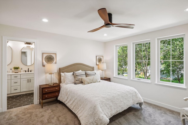 carpeted bedroom with ceiling fan, ensuite bathroom, and sink