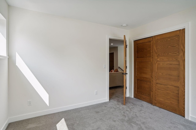 unfurnished bedroom with light colored carpet and a closet