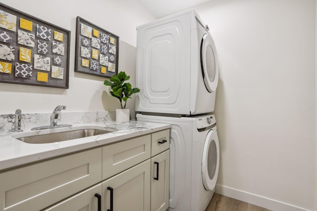 laundry room with light hardwood / wood-style floors, stacked washer and dryer, cabinets, and sink