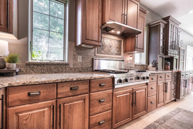 kitchen featuring tasteful backsplash, light stone countertops, stainless steel gas cooktop, and a textured ceiling