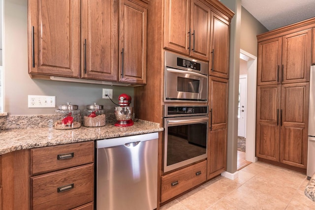 kitchen with light tile patterned flooring, appliances with stainless steel finishes, and light stone counters