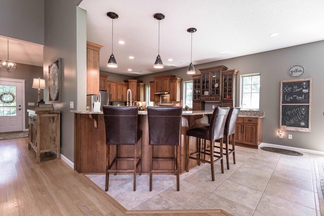 kitchen with pendant lighting, a breakfast bar, stainless steel fridge, and kitchen peninsula