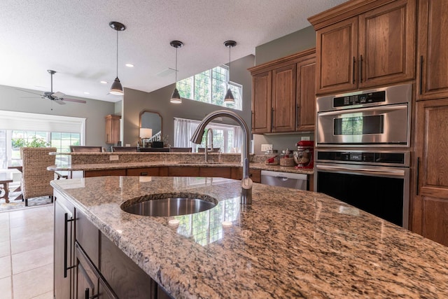 kitchen featuring sink, stainless steel appliances, light stone countertops, a textured ceiling, and light tile patterned flooring