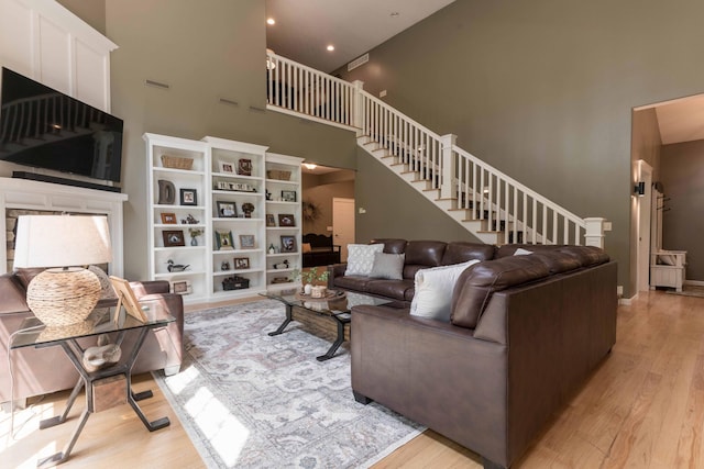 living room featuring a towering ceiling and light hardwood / wood-style flooring