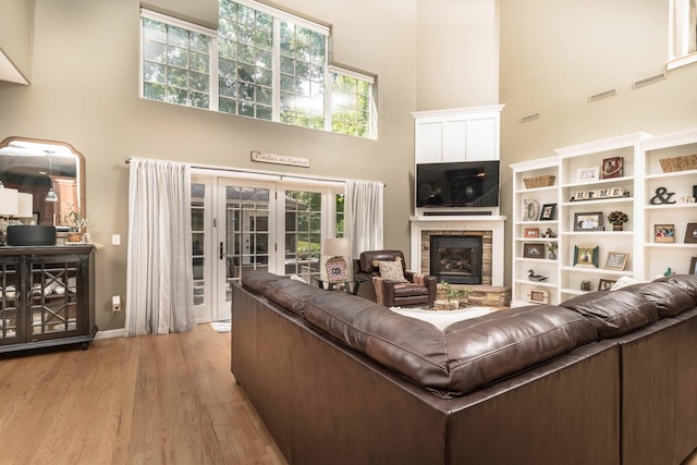 living room with a towering ceiling, french doors, and light wood-type flooring