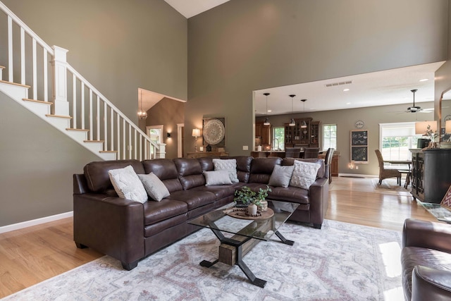 living room featuring ceiling fan, light hardwood / wood-style flooring, and a high ceiling