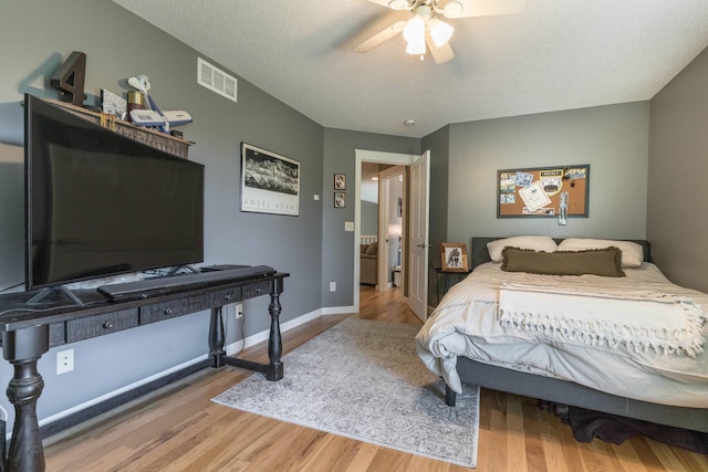 bedroom with hardwood / wood-style flooring, a textured ceiling, and ceiling fan