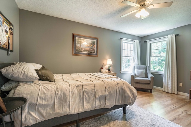 bedroom featuring ceiling fan, a textured ceiling, and light hardwood / wood-style floors