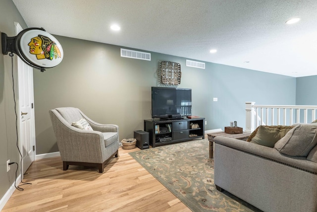 living room with a textured ceiling and light wood-type flooring