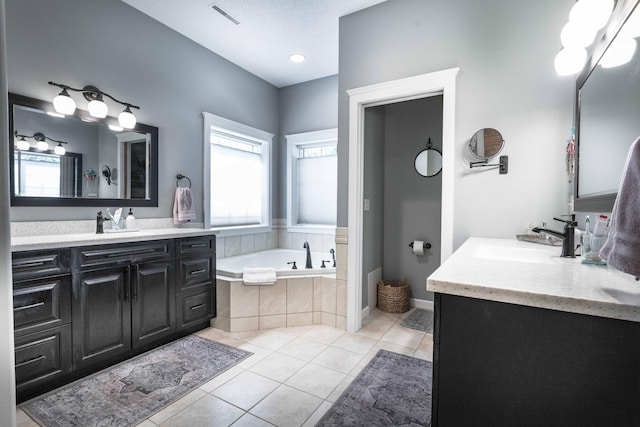 bathroom featuring a relaxing tiled tub, vanity, tile patterned flooring, and a textured ceiling