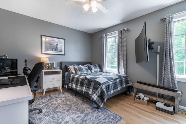 bedroom with ceiling fan, a textured ceiling, and light wood-type flooring