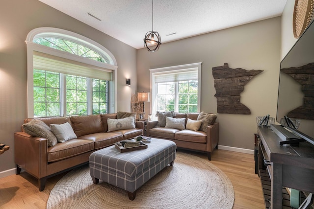 living room with lofted ceiling, light hardwood / wood-style flooring, and a textured ceiling