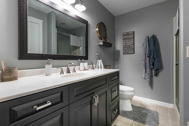 bathroom with vanity, a shower with shower door, tile patterned floors, and toilet