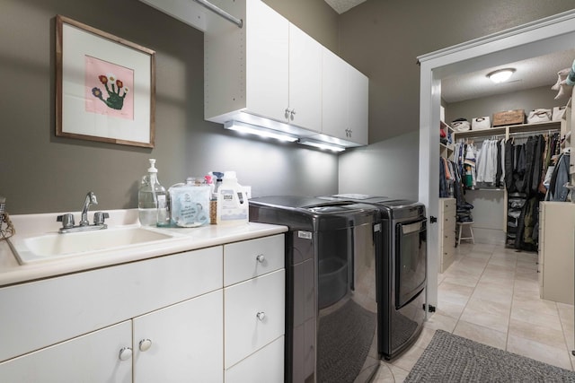 laundry area featuring sink, light tile patterned floors, washing machine and dryer, and cabinets