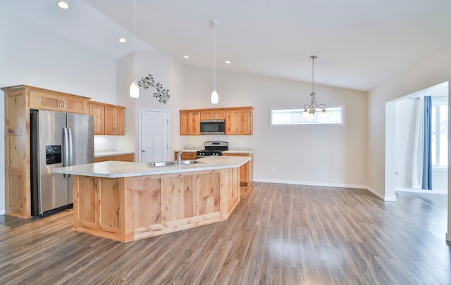 kitchen featuring appliances with stainless steel finishes, an island with sink, sink, hanging light fixtures, and dark wood-type flooring