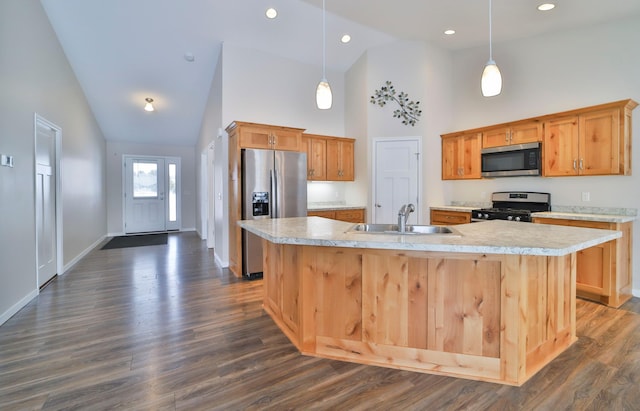 kitchen with pendant lighting, stainless steel appliances, sink, and an island with sink