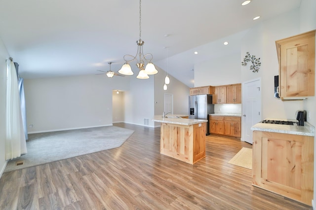 kitchen featuring a kitchen island with sink, sink, light wood-type flooring, and decorative light fixtures