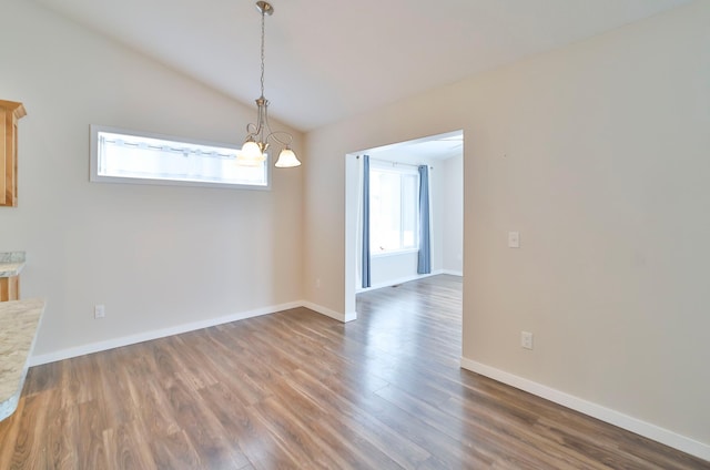 unfurnished dining area featuring lofted ceiling, dark hardwood / wood-style floors, and an inviting chandelier