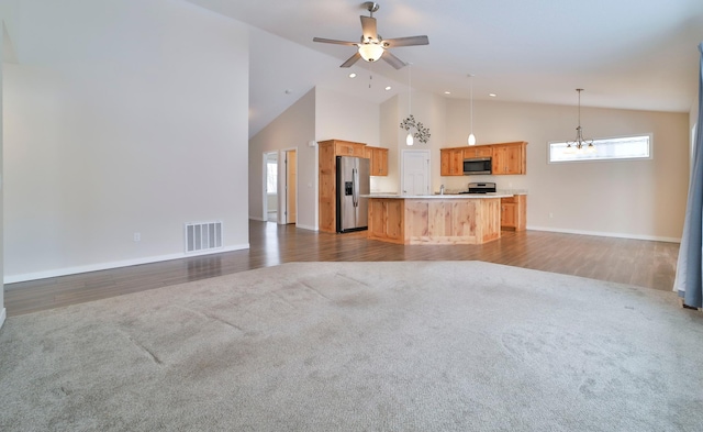 kitchen featuring appliances with stainless steel finishes, decorative light fixtures, dark carpet, and a kitchen island