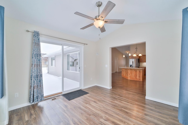 spare room with lofted ceiling, hardwood / wood-style flooring, and ceiling fan with notable chandelier