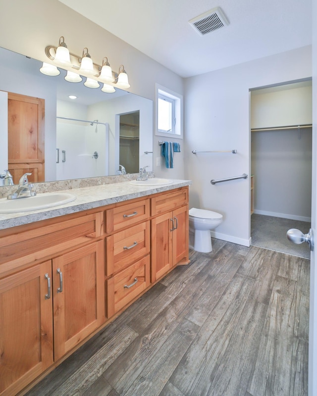 bathroom featuring hardwood / wood-style flooring, vanity, toilet, and a shower with shower door