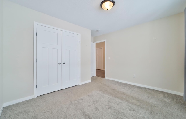 unfurnished bedroom featuring light carpet and a closet