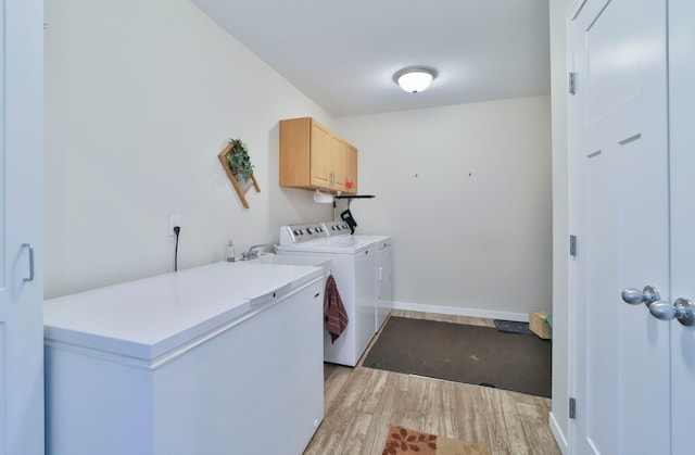 laundry area with light hardwood / wood-style floors, cabinets, and washing machine and clothes dryer