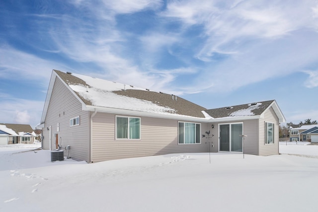 snow covered back of property featuring central AC