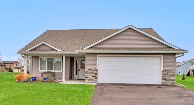 view of front of home featuring driveway, stone siding, a garage, a front lawn, and a shingled roof