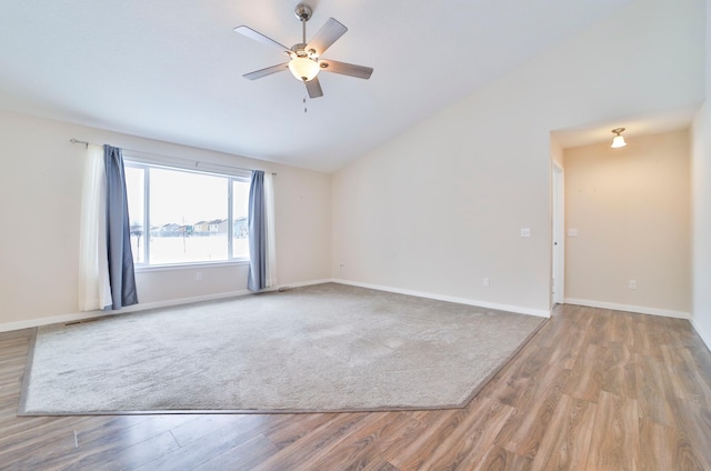 unfurnished room with wood finished floors, a ceiling fan, vaulted ceiling, and baseboards