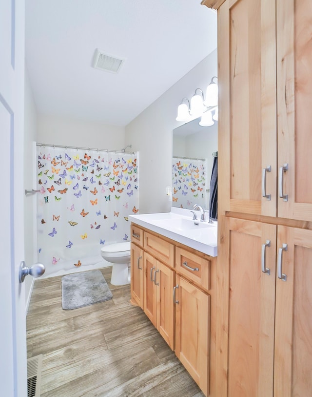 bathroom with wood finished floors, vanity, toilet, and curtained shower